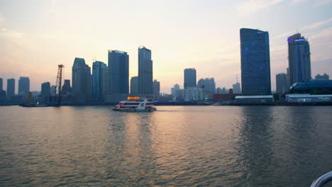 Sightseeing-Boot-Nimmt-Touristen-Mit-Auf-Eine-Abendliche-Tour-Auf-Shanghais-Berühmtem-Huangpu-Fluss,-Bei-Der-Spektakuläre-Lichter-Auf-Nahe-Gelegenen-Geschäftsgebäuden-Zur-Schau-Gestellt-Werden
