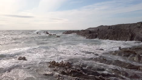 Right-to-Left-Pan-of-Waves-Crashing-Against-a-Rocky-Cove-on-a-Summer’s-Evening