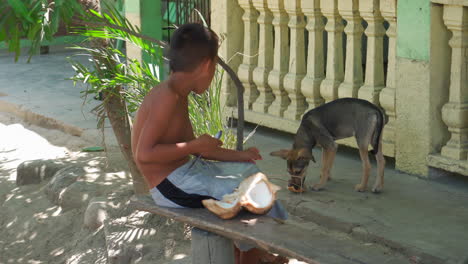 Ein-Junger-Honduranischer-Junge-Sitzt-Im-Nachmittagsschatten-Und-Isst-Eine-Kokosnuss