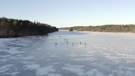 An-aerial-drone-shot-of-a-group-of-people-ice-skating-on-a-large-frozen-lake---Daytime