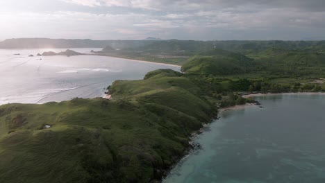Toma-Aérea-En-órbita-Sobre-La-Isla-De-Lombok-Con-Las-Famosas-Colinas-De-Bukit-Merese-Y-Playas-De-Arena-Con-Olas-Rompientes-Del-Océano