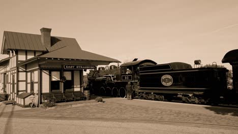Eine-Schwarz-Weiß-Ansicht-Aus-Den-1950er-Jahren-Einer-Antiken-Dampflokomotive-An-Einem-Bahnhof-Mit-Einem-Fahrgast,-Der-Mit-Dem-Ingenieur-Spricht
