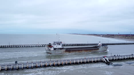 Aerial-pan-right-shot-of-boat-entering-Nieuwpoort-port-on-cloudy-day