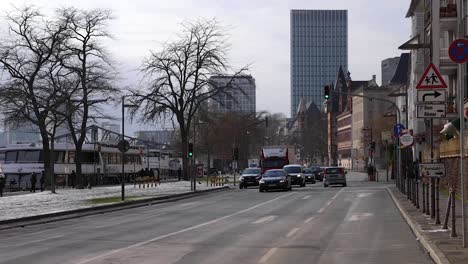 Vehicle-Driving-Along-Main-Quay,-Mainkai-Street-On-The-Bank-Of-Main-River-Near-Skyline-In-Frankfurt,-Germany