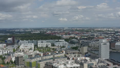 Sprawling-city-of-Helsinki-on-river-with-green-park,-long-drone-shot