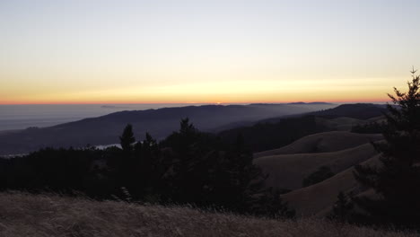 The-sun-dipping-below-the-horizon-on-Mount-Tamalpais-with-tall-grass-in-the-foreground
