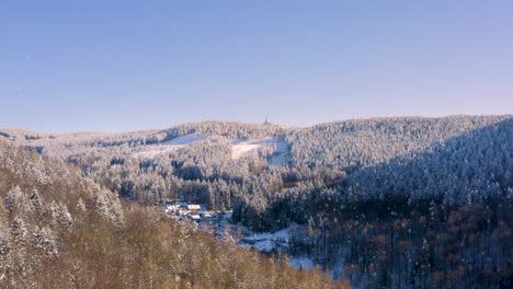 Dorf-Unterhalb-Eines-Bergkamms-Im-Schneefall,-Darüber-Funkturm