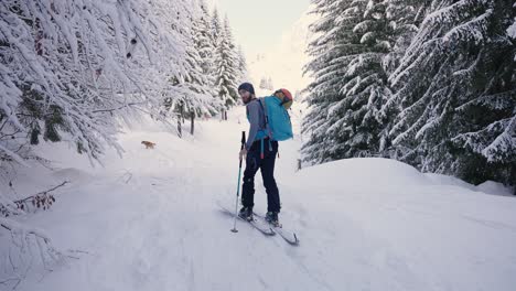 Smiling-skier-man-walking-in-forest-and-looking-back-into-camera