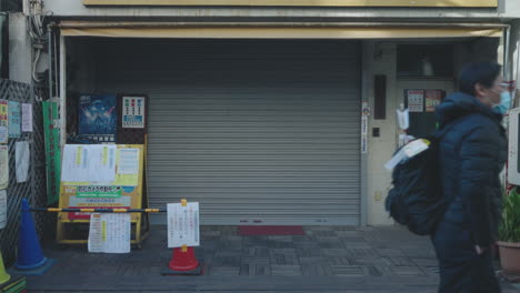 Personas-Que-Pasan-Por-Un-Establecimiento-De-Puestos-Cerrados-Debido-A-Una-Crisis-En-Medio-De-Una-Pandemia-En-Tokio,-Japón