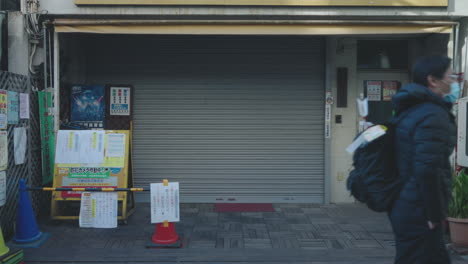 Menschen,-Die-Aufgrund-Einer-Krise-Inmitten-Einer-Pandemie-In-Tokio,-Japan,-An-Einem-Geschlossenen-Stall-Vorbeikommen