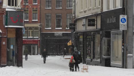 Mother-and-son-with-sled-in-The-Netherlands-in-historic-city-centre-in-the-snow-with-the-streets-white-of-the-heavy-precipitation