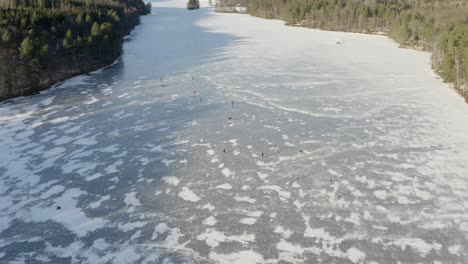 Leute,-Die-Auf-Einem-Zugefrorenen-See-Schlittschuh-Laufen---4K-Drohne-Luftbild