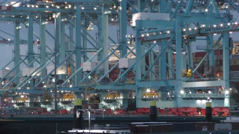 Quay-Cranes-At-Work-At-The-APM-Terminal,-Logistic-Service-In-Maasvlakte,-Rotterdam,-Netherlands-At-Dusk