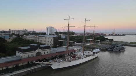 Aerial-rising-of-famous-ARA-Libertad-frigate-docked-in-Puerto-Madero-at-golden-hour,-Buenos-Aires
