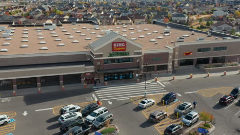 Descending-Aerial-drone-footage-of-King-Soopers-grocery-store-with-a-Fedex-truck-arriving-in-front