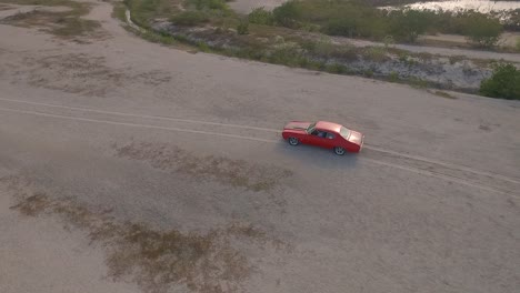 Vista-De-Drones-De-Un-Viejo-Muscle-Car-Americano-En-Un-Desierto-Durante-Una-Puesta-De-Sol