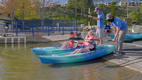 Dos-Niños-Preadolescentes-Metiéndose-En-Kayaks-Oceánicos-En-El-Lago-De-Mission-Viejo,-California