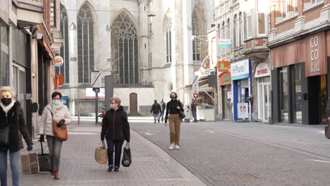 Crowd-of-people-wear-compulsory-face-masks-in-downtown-Leuven-shopping-street,-Covid-19-coronavirus-in-Belgium
