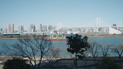 Regenbogenbrücke-über-Der-Bucht-Von-Tokio-Mit-Denkmal-Der-Olympischen-Ringe-An-Einem-Sonnigen-Tag-In-Odaiba,-Minato,-Tokio,-Japan