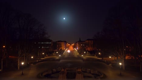 Lonely-long-street-in-Munich-in-times-of-Corona-and-the-Covid-19-lockdown-under-the-shining-full-moon-with-the-view-at-the-cityscape-of-the-bavarian-popular-city,-nearly-empty-at-night