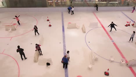 Se-Ve-A-Personas-De-Todas-Las-Edades-Disfrutando-Y-Aprendiendo-Patinaje-Sobre-Hielo-Bajo-Techo-En-Un-Centro-Comercial-En-Hong-Kong