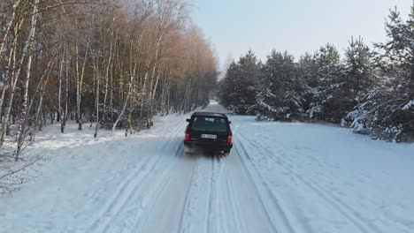 Low-aerial-shot-following-a-car-driving-off-road-on-snow-in-a-forest-of-Norway