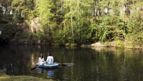 Newlywed-couple-rowing-on-a-small-boat-on-a-small-forest-lake,summer