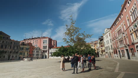 Slow-motion-dolly-shot-of-female-tour-guide-with-group-of-tourist-exploring-the-city-of-Venice-during-beautiful-summer-day