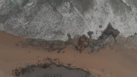 Top-down-static-shot-over-ocean-waves-crashing-on-Ponta-da-Calheta-beach,-Porto-Santo-island