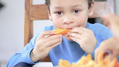 Un-Niño-Pequeño-Disfrutando-De-Una-Fruta-Naranja-Promoviendo-Una-Alimentación-Saludable-Almacen-De-Metraje-De-Video
