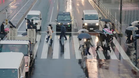 Fahrzeuge,-Die-Darauf-Warten,-Dass-Menschen-Mit-Regenschirm-In-Einer-Regnerischen-Nacht-In-Shinjuku,-Tokio,-Japan,-Die-Straße-überqueren