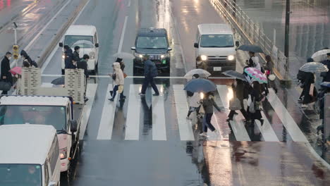 Vehicles-Waiting-For-People-With-Umbrella-To-Cross-The-Road-On-A-Rainy-Night-In-Shinjuku,-Tokyo,-Japan