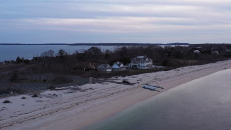 an-aerial-view-over-a-narrow-beach-in-Orient-Point,-New-York-during-a-cloudy-sunset