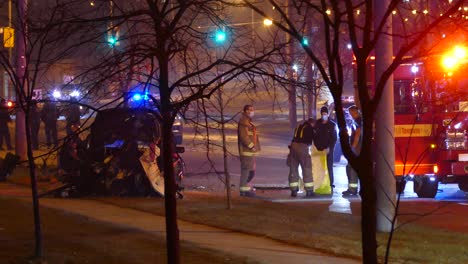 Firefighters-standing-near-a-car-crash-during-the-night-in-a-street-in-Toronto,-Canada