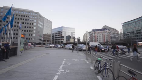 Gente-Caminando-Y-Cruzando-La-Calle-En-La-Rotonda-De-Schuman-Con-El-Tráfico-De-La-Ciudad-Durante-La-Pandemia-En-Bruselas,-Bélgica