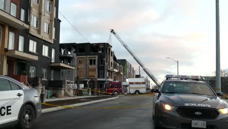 Fire-fighter-in-top-of-aerial-ladder-spraying-water-on-burning-house