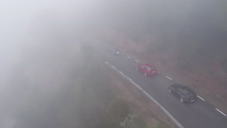 Aerial-view-following-close-rear-to-high-end-expensive-cars-driving-misty-winding-Barcelona-mountain-roads