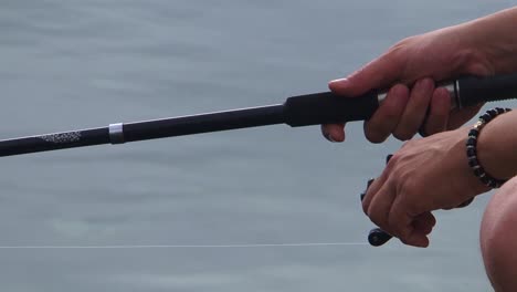 Hand-spinning-the-machine-on-the-fishing-rod-above-water