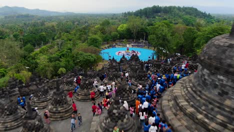 Buddhist-temple-Borobudur,-Java-travel-destination-crowded-by-tourists,-aerial-dolly-out