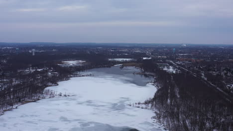 An-aerial-view-from-a-drone,-over-a-long-lake-during-sunrise-on-a-cloudy-morning