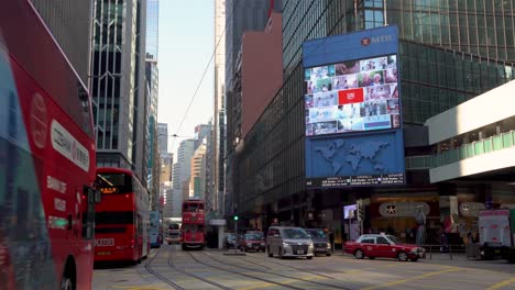 Street-Traffic-and-Public-Transportation,-Central-Hong-Kong,-Double-Decker-Buses-and-Tram-Under-Skyscrapers,-Static-View