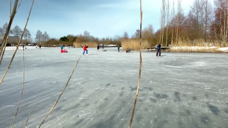 People-enjoy-on-a-frozen-pond-in-a-city-park-during-the-freezing-cold-in-February,-which-lasted-only-one-week-in-the-Netherlands-in-2021