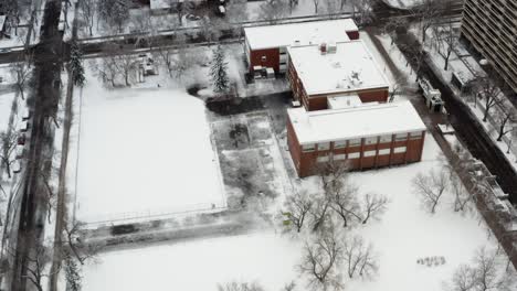 Bird-Eye-View-fly-over-Grandin-Elementary-School-in-downtown-Edmonton-Capital-City-of-Alberta-during-the-2nd-biggest-snow-of-the-season-early-on-a-Sunday-morning-where-the-streets-are-empty-no-one-out