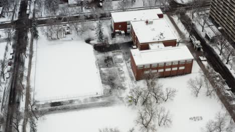 Vista-De-Pájaro-Volar-Sobre-La-Escuela-Primaria-Grandin-En-El-Centro-De-Edmonton,-Capital-De-Alberta,-Durante-La-Segunda-Nevada-Más-Grande-De-La-Temporada-Temprano-Un-Domingo-Por-La-Mañana-Donde-Las-Calles-Están-Vacías,-Nadie-Sale