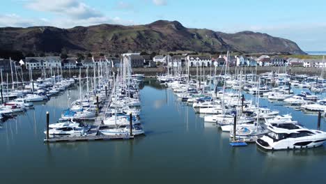 Luxury-yachts-and-sailboats-moored-in-Conwy-marina-mountain-waterfront-aerial-view-North-Wales-slow-dolly-right