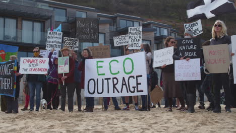 Kleiner-Junge-Schließt-Sich-Demonstranten-An,-Die-Zusammen-Am-Strand-Gegen-Carbis-Bay-Hotel,-Cornwall,-Stehen