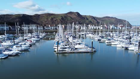 Luxury-yachts-and-sailboats-moored-in-Conwy-marina-mountain-waterfront-aerial-view-North-Wales-low-right-dolly