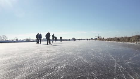 Gente-Patinando-Sobre-Hielo-En-Canales-Congelados-En-Tierra-De-Pólder-De-Holanda-Cerca-De-Molinos-De-Viento