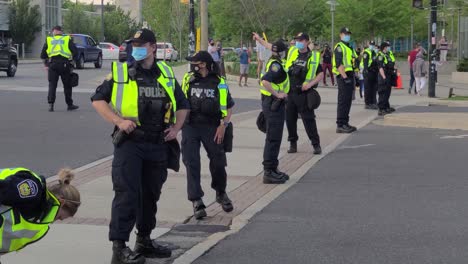 Línea-De-Policías-Con-Chaleco-Reflectante-Y-Mascarilla-En-Guardia-Durante-La-Protesta-Pro-palestina-En-Ontario,-Canadá-Durante-El-Día