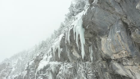 Low-angle-dolly-of-large-icicles-hanging-of-mountain-ridge